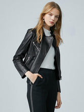A woman in a black leather jacket stands with one hand in her pocket.